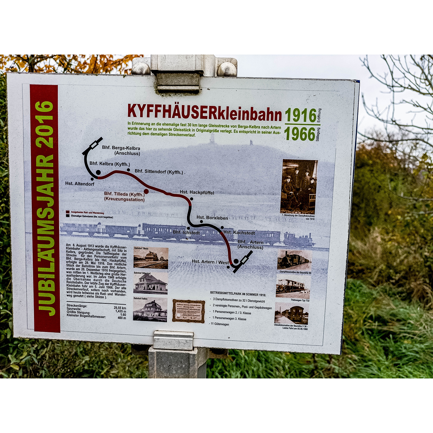 31-Goldene Aue - Berga - Blick nach Südosten auf Schild Kyffhäuserkleinbahn zwischen Gebäude Bahnhofstraße 21 b & B 85